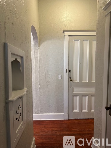 A white door with a black handle is in a room with wooden floors.