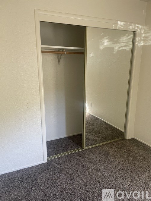 A white closet with a mirror door is open.