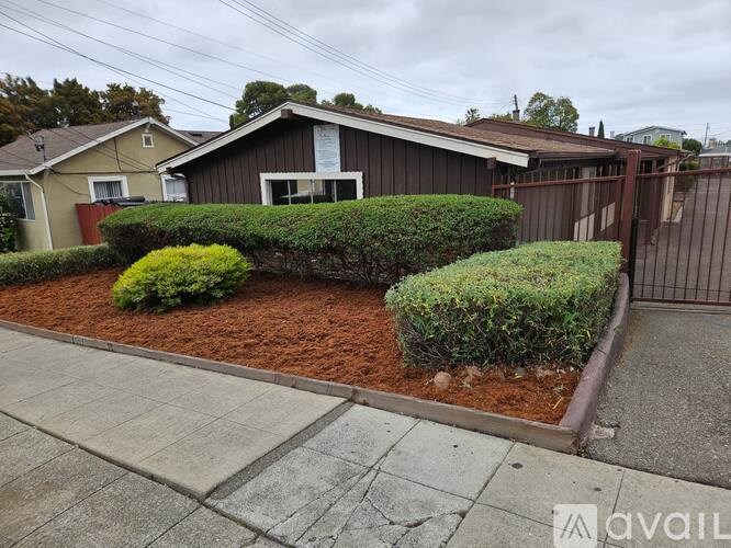 A house with a brown fence and a green bush in front.