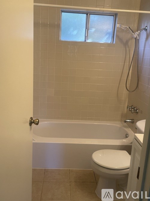 A bathroom with a toilet, tub, and window.