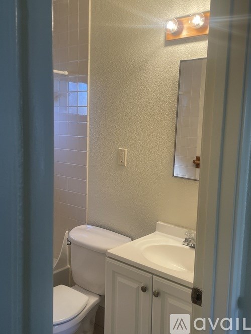 A bathroom with a toilet, sink, and mirror.