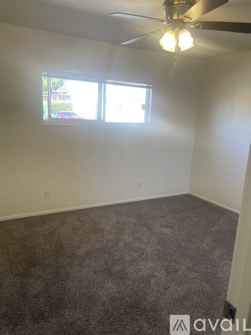 A room with a ceiling fan and carpeted floor.