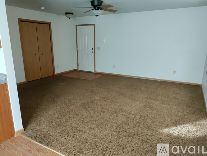 A room with a carpeted floor and a ceiling fan.