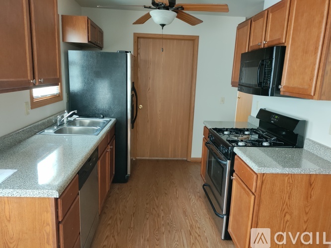 A kitchen with wooden cabinets and a black fridge.