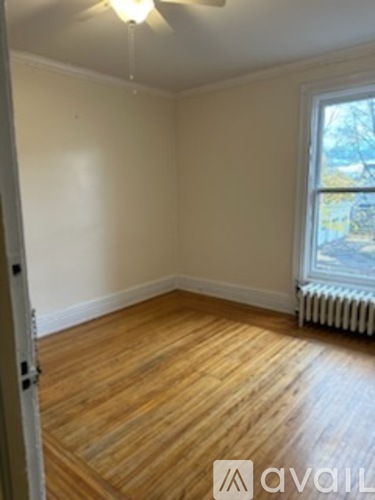 A room with wooden floors and a window with a view of trees outside.