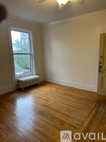 A room with wooden floors and a window with a radiator beneath it.