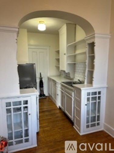 A kitchen with white cabinets and a black television.
