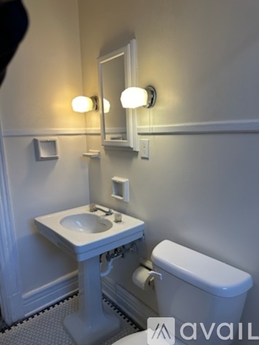 A white bathroom with a toilet, sink, and mirror.