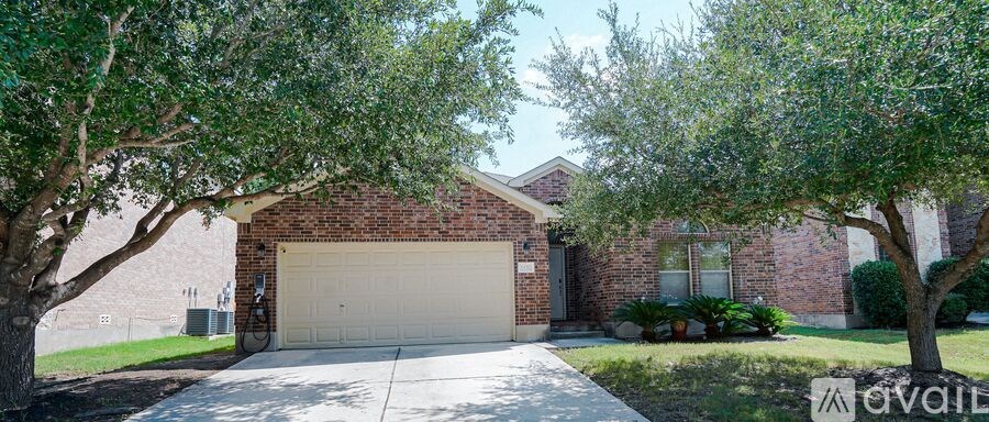 A house with a garage is surrounded by trees.