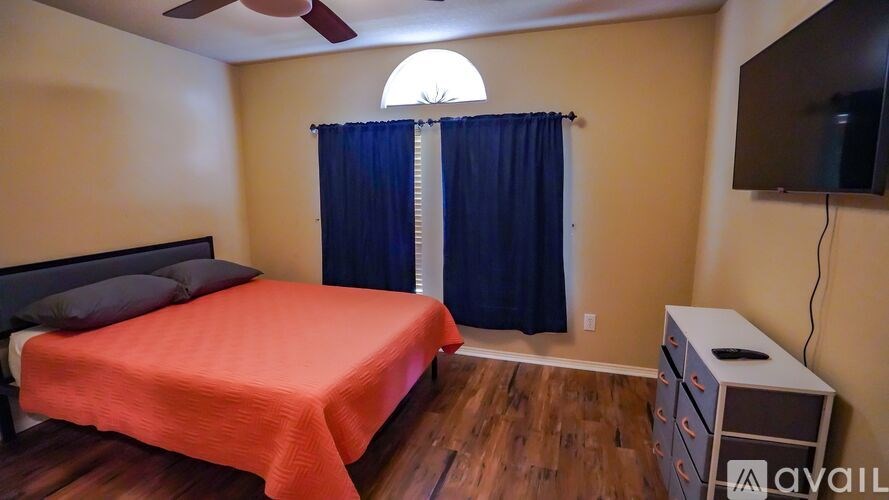 A bedroom with a bed, a dresser, and a ceiling fan.