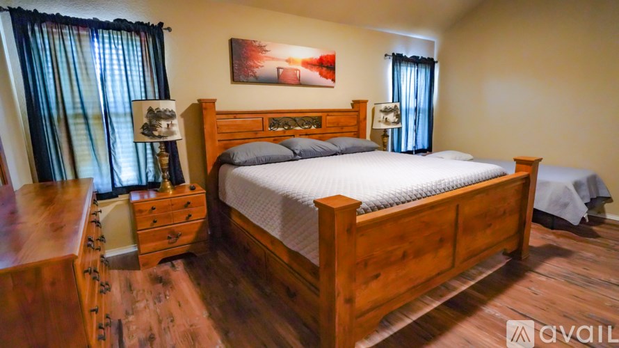 A bedroom with a large bed, a nightstand, and a dresser.