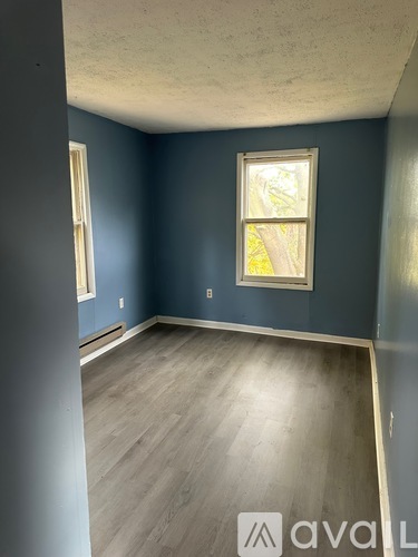 A room with a window and a wooden floor.