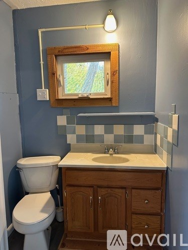 A bathroom with a toilet, sink and mirror.