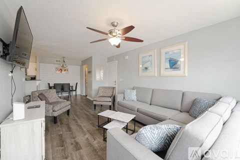 A living room with a grey couch and a ceiling fan.