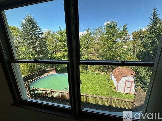 A view from a window looking out at a pool and a house.