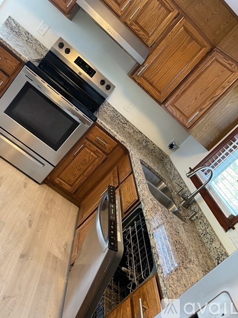 A kitchen with wooden cabinets and a stainless steel dishwasher.