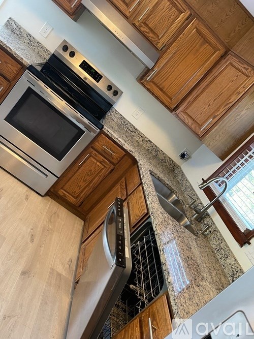 A kitchen with wooden cabinets and a stainless steel dishwasher.