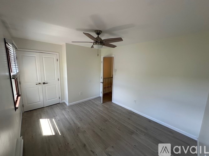 A room with a ceiling fan and wooden flooring.