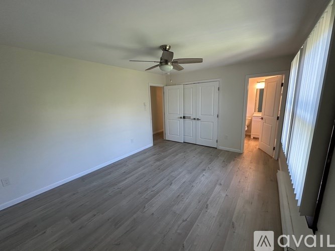 A room with a ceiling fan and wooden flooring.
