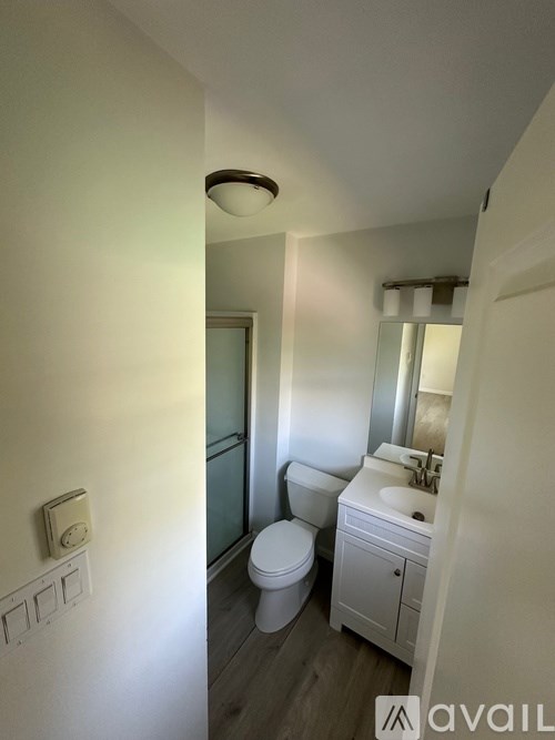 A bathroom with a toilet, sink, and mirror.