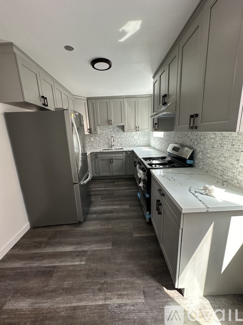A kitchen with a refrigerator, stove, and cabinets.