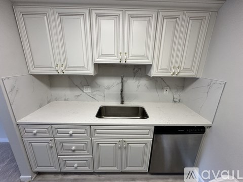 A kitchen with white cabinets and a marble countertop.