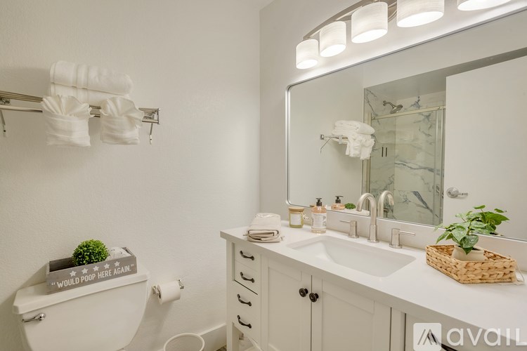 A bathroom with a toilet, sink, mirror, and towel rack.
