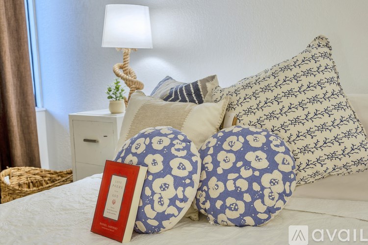 A bed with blue and white patterned pillows and a red book.