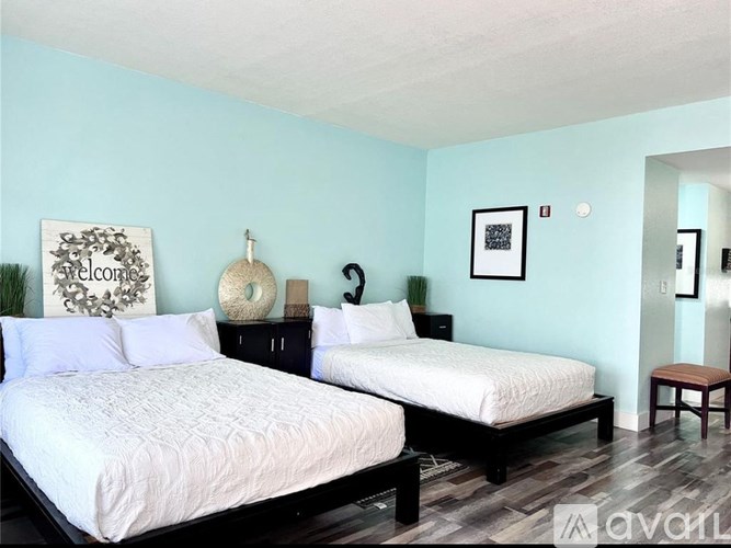 Two beds in a room with a blue wall and a white bedspread.
