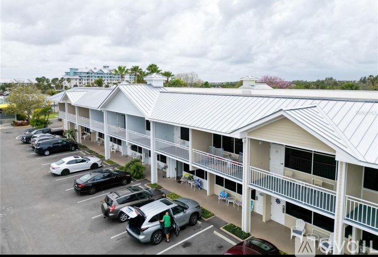 A parking lot with cars and a building with a metal roof.