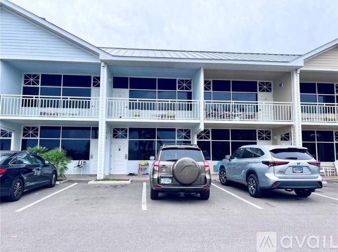 A parking lot with cars and a building with a balcony.