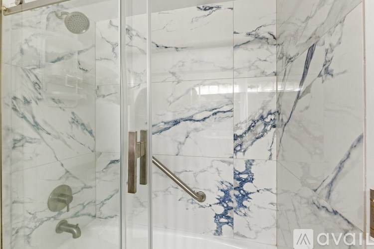 A shower with a glass door and marble tiles.