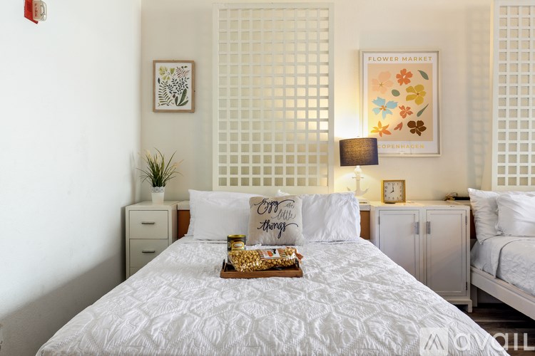 A bedroom with a large bed, a nightstand, and a wall hanging with the text "Flower Market".