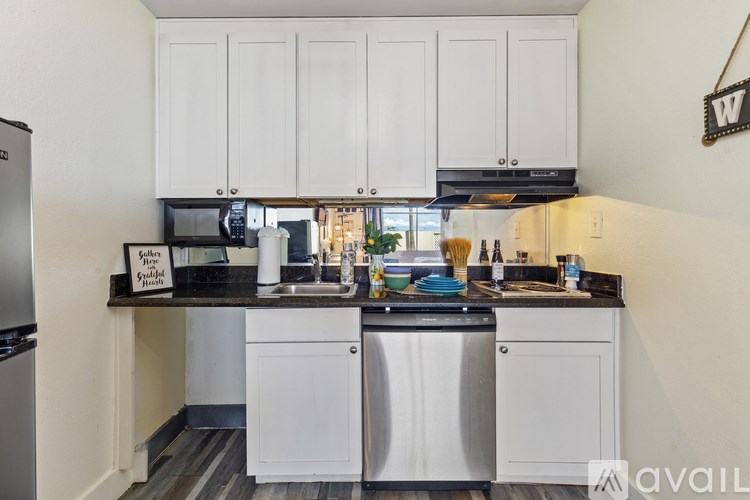 A kitchen with white cabinets and a black counter top.