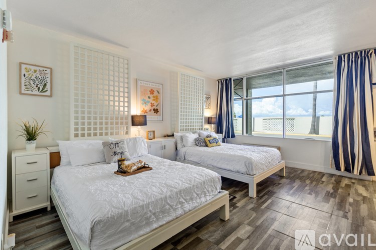 A bedroom with two beds and a nightstand.