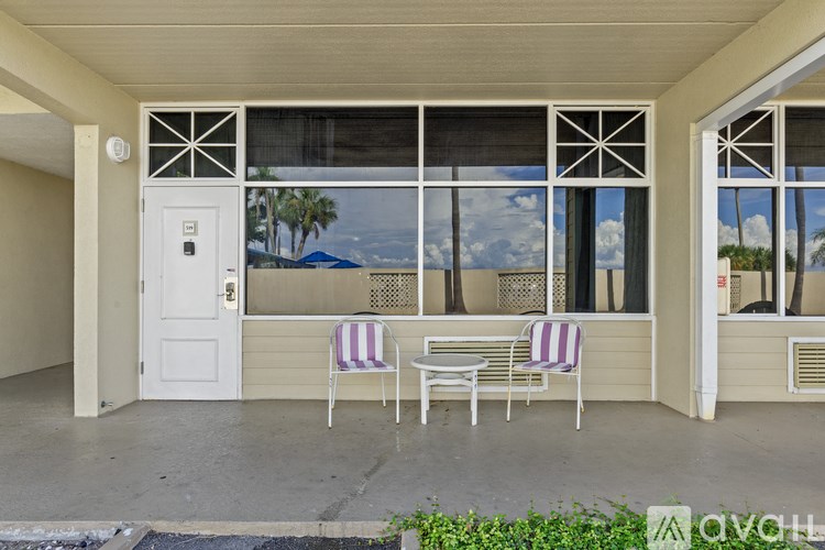A patio with a table and chairs is shown with a view of the ocean.