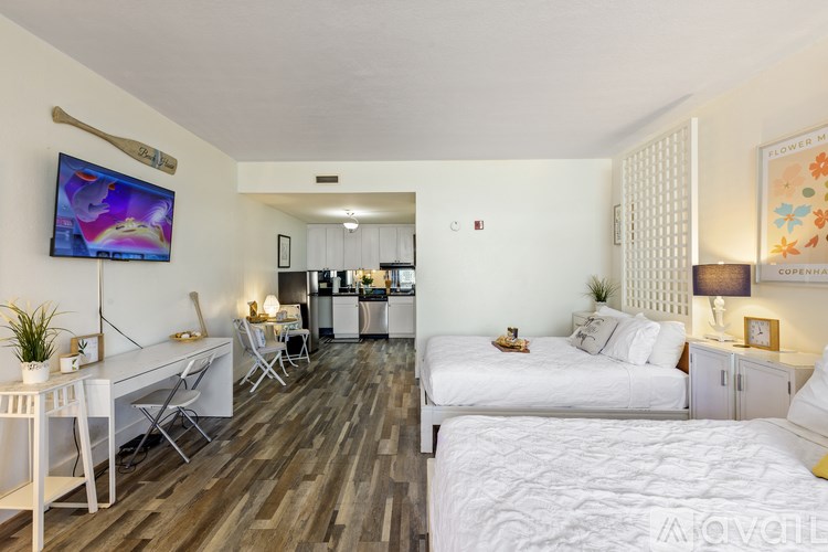 A bedroom with a white bed and a television mounted on the wall.