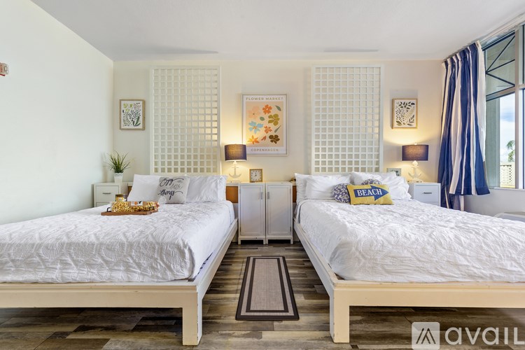 Two twin beds in a room with white walls and wooden floors.