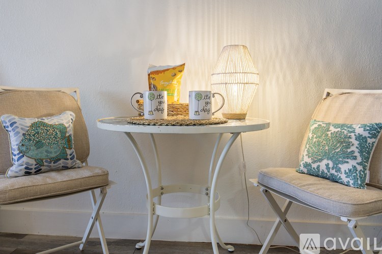 A white table with a lamp and two chairs with cushions.