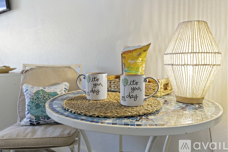 A table with two cups and a bag of snacks on it.