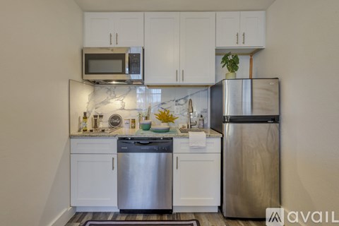 A kitchen with white cabinets and a marble backsplash.