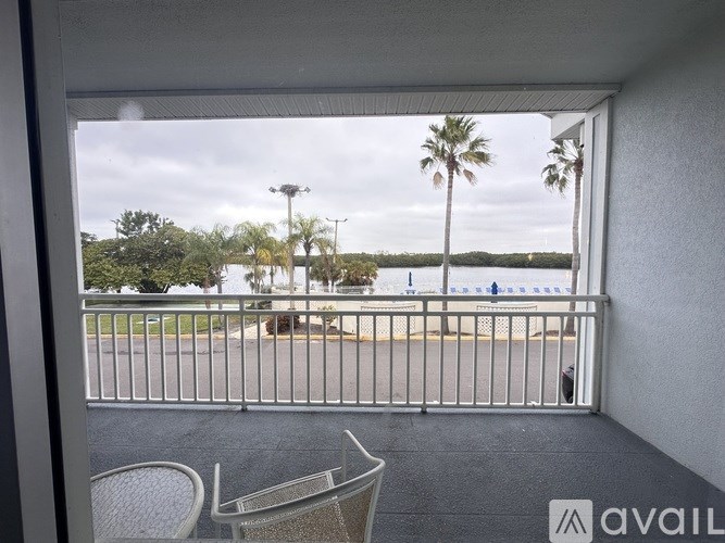 A balcony with a table and chairs overlooking a parking lot.
