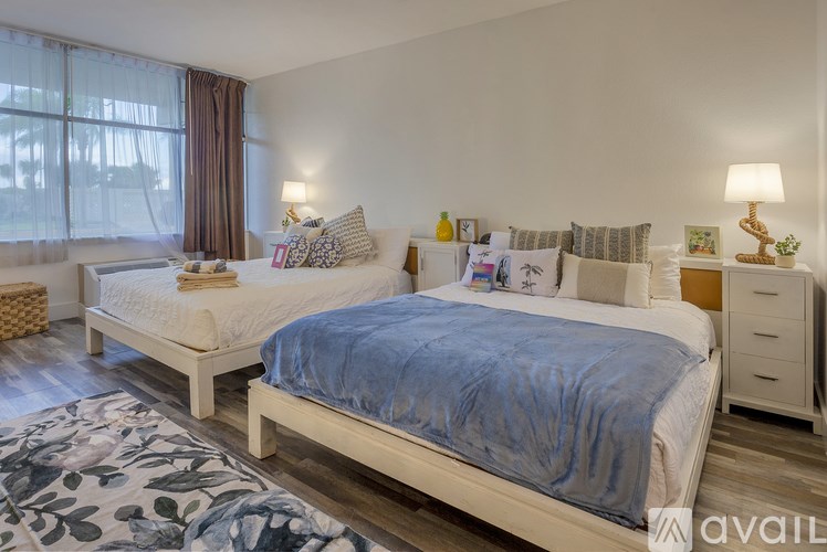 A bedroom with two beds, one with a blue bedspread and the other with a white bedspread.