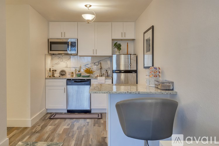 A kitchen with a grey chair and a marble counter.