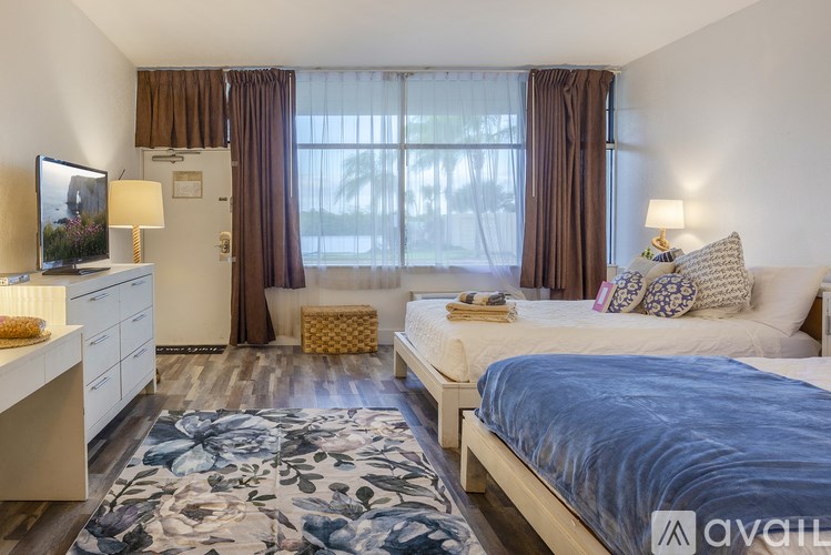 A bedroom with a large bed, a TV, and a window with curtains.