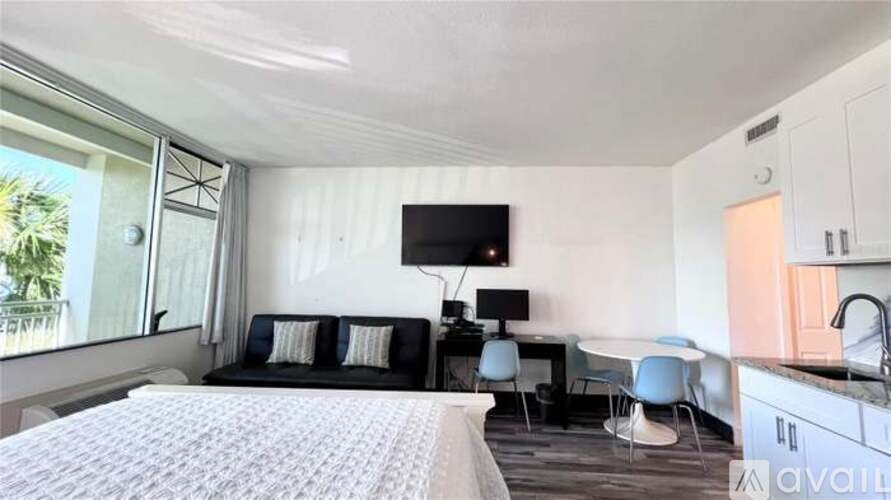 A bedroom with a large bed, a desk with a chair, and a television mounted on the wall.