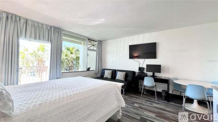 A bedroom with a large bed, a desk with a chair, and a window with curtains.