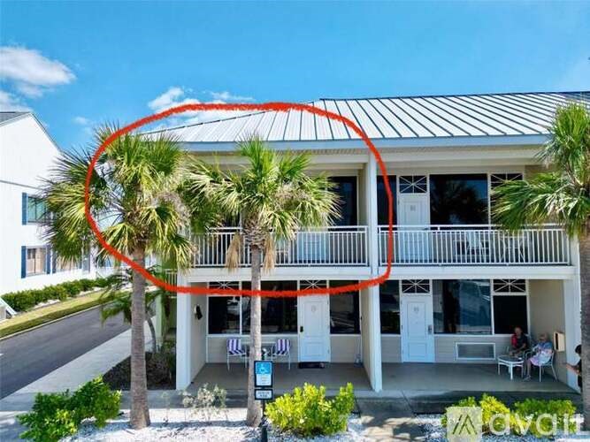 A house with a balcony and a palm tree in front.