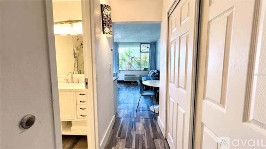 A hallway with a door on the left and a table with chairs in the distance.