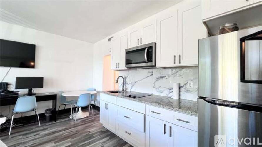 A kitchen with white cabinets and a marble countertop.
